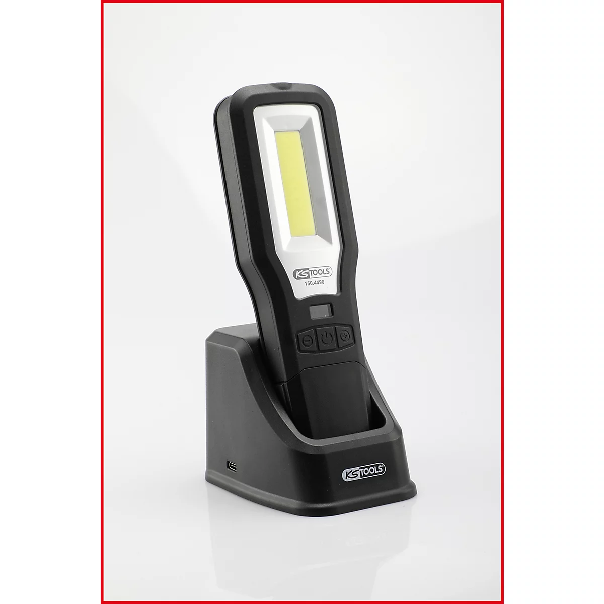 Zwarte werkplaatslamp in laadstation. De kop heeft een rechthoekig, helder LED-gebied.